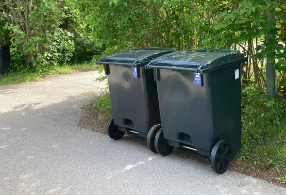 Soptunna för matavfall och soptunna för restavfall står ohämtade på trottoaren.